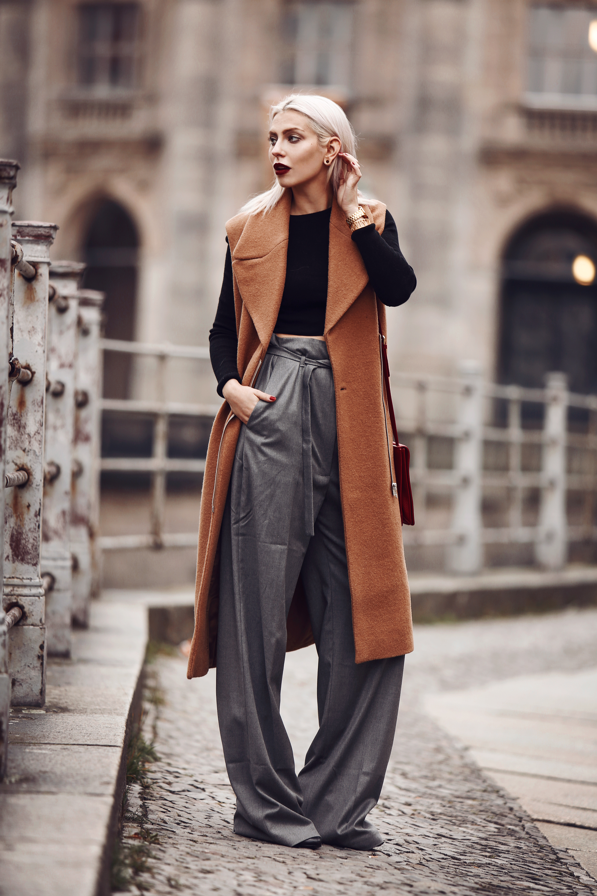 Outfit: Casual Business via Masha Sedgwick | wearing a classy red bag from Aigner, wide grey marlene trousers from Carin Wester, black crop top, a brown wool vest | street style from Berlin | effortless chic