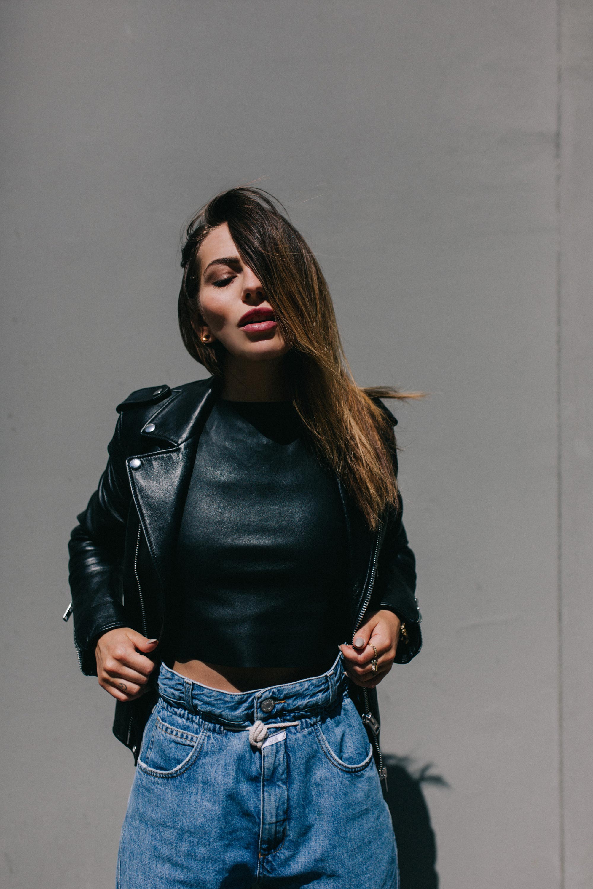 Fashion Editorial in the sun | Light Aesthetic | black leather jacket & blue paperbag jeans | neutral & minimalistic | concrete wall