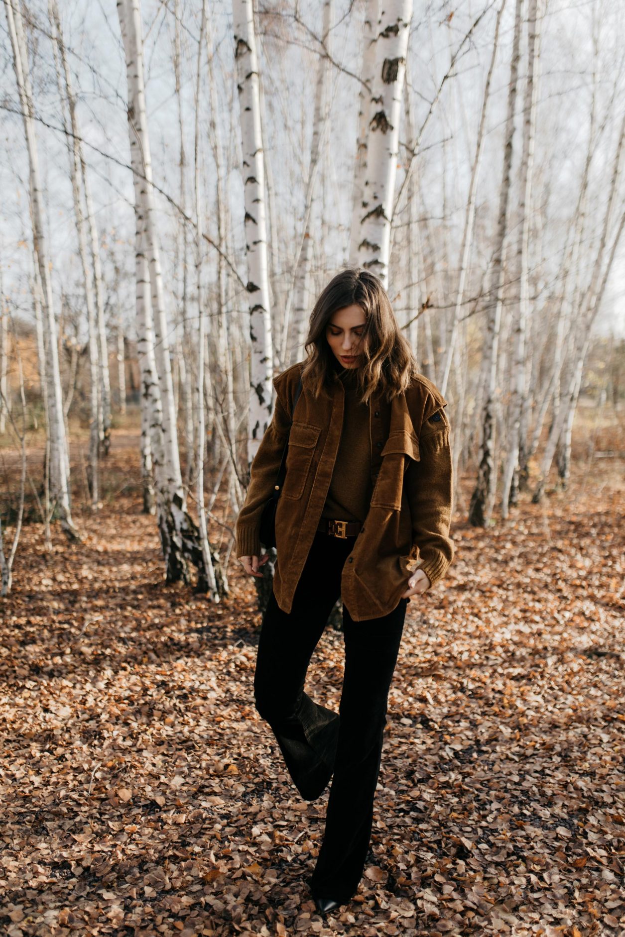 Streetstyle by Masha Sedgwick | Fall winter country style outfit, wearing  tobacco Closed pullover, tobacco cord west by Closed, bootcut jeans by J Brand, brown Escada belt, black black leather cross body bag By Malene Birger | Berlin photo spot: birch park