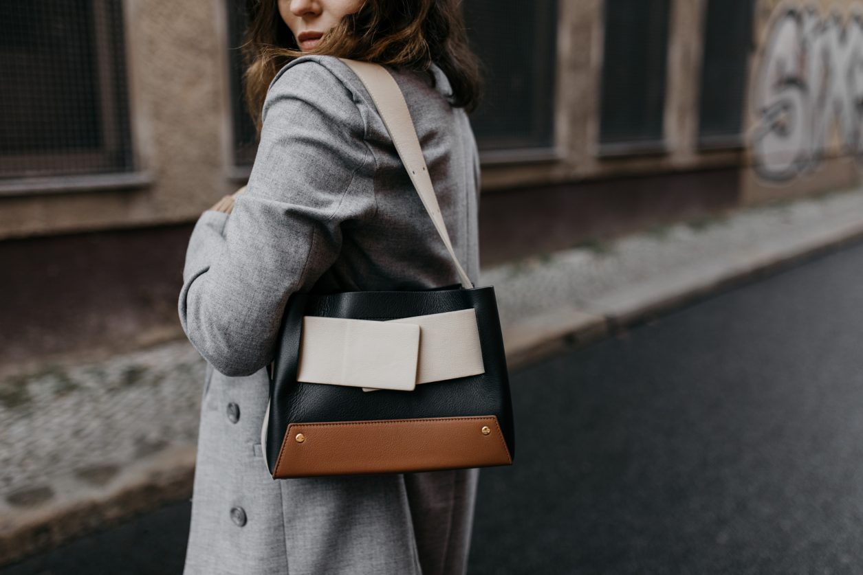 Streetstyle by Masha Sedgwick | Early spring city outfit inspiration, wearing beige classic Closed coat, beige-brown-black Yuzefi shoulder bag, grey Closed jeans, black &other Stories loafer with zipper, grey socks, grey Gestuz blazer, wrapped brown Baum & Pferdgarten shirt | Berlin street style editorial shooting