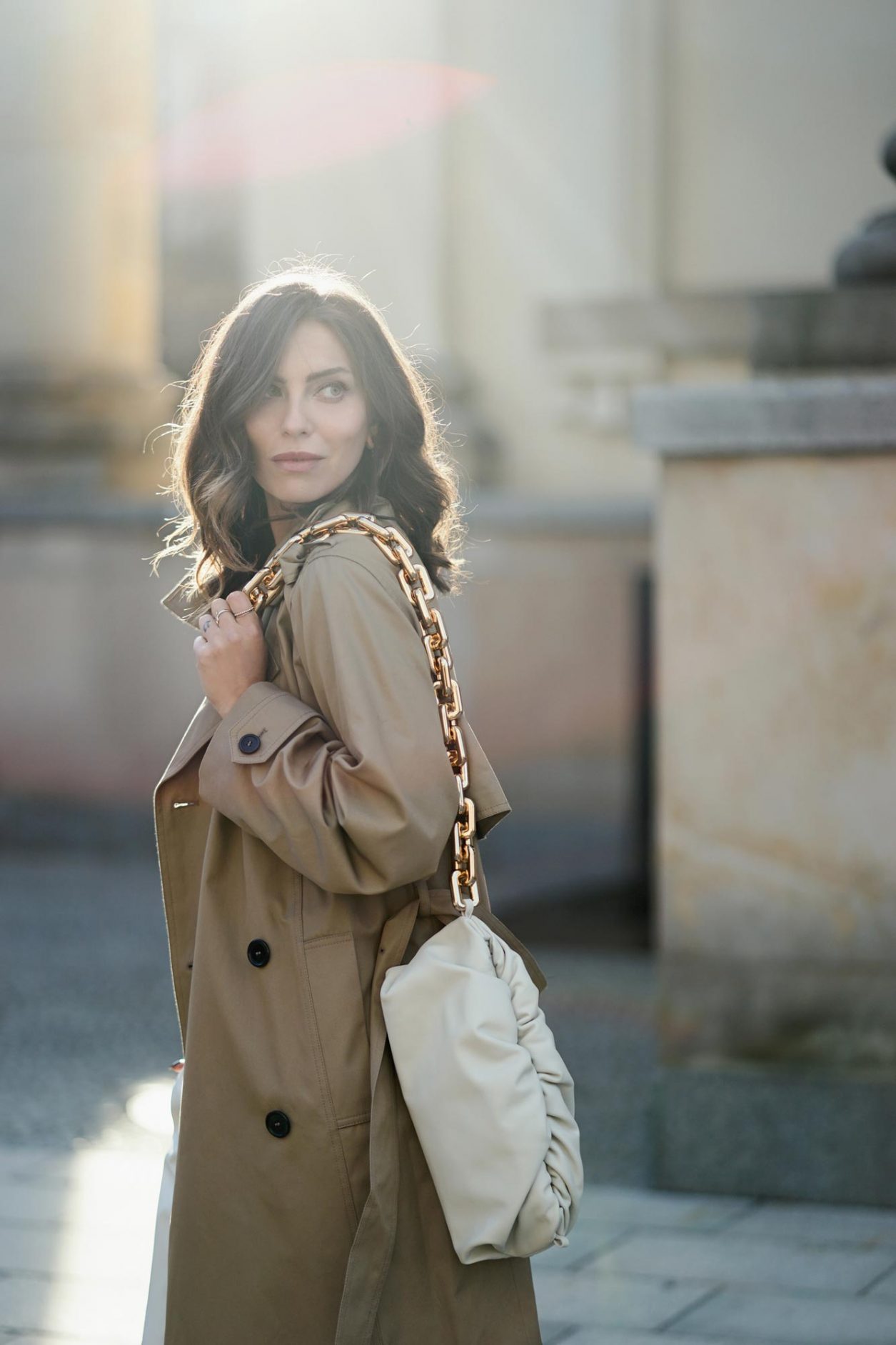 Portrait by Masha Sedgwick | Fashion blogger from Berlin, Germany | Spring outfit inspiration: wearing beige Saint Laurent trench coat, white Maison Margiela pants, the white Bottega Venetta chain pouch, black Acne Studio basic logo shirt