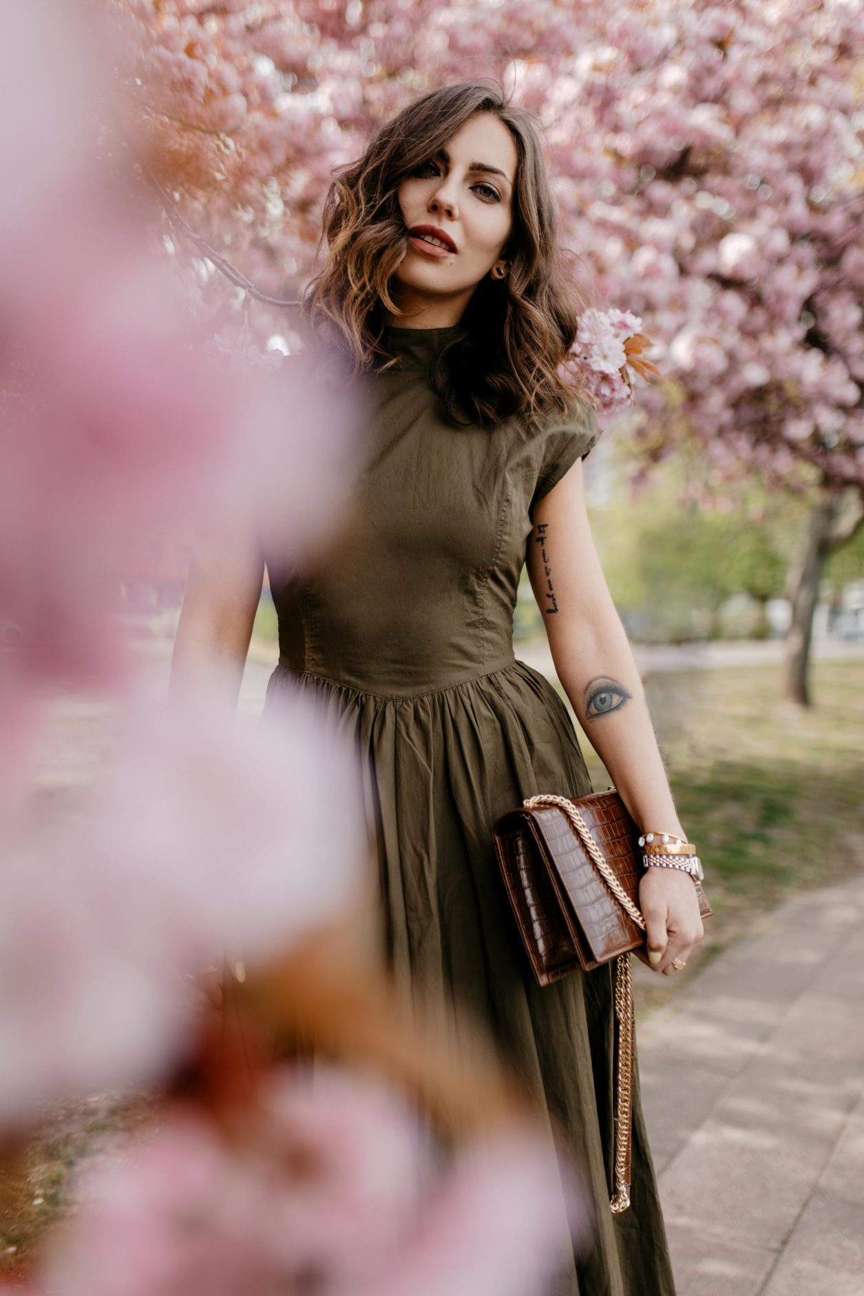 Anzeige | Streetstyle by fashion blogger Masha Sedgwick | Wearing khaki green midi dress with open back by Gestuz, black heeled sandals from Office via Zalando, brown leather cross-body bag with golden chain from Agneel | Minimalistic effortless cool outfit, city chic look, shooting spot: Berlin, cherry blossom