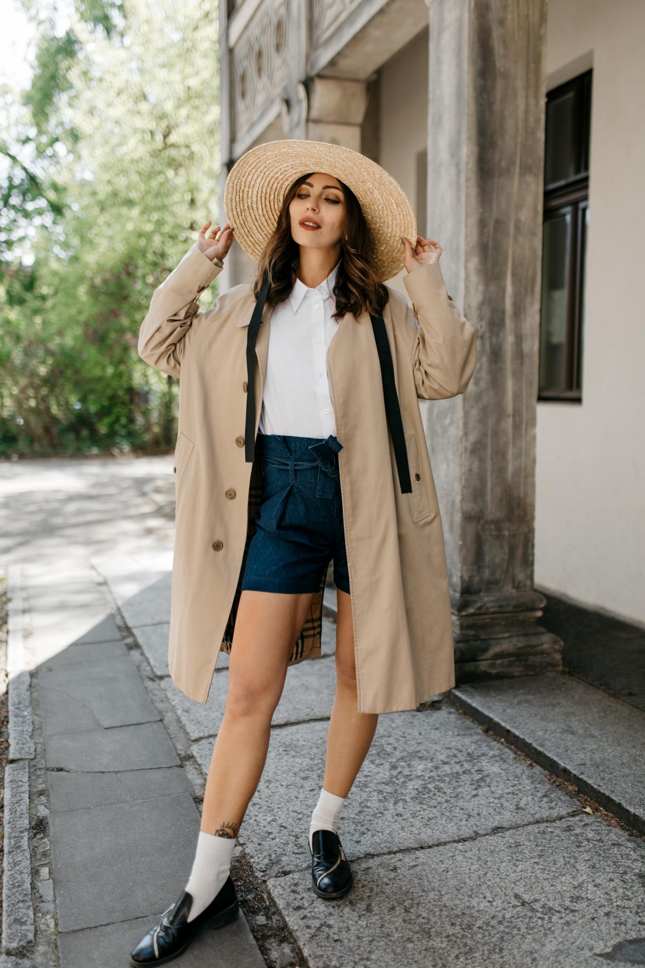 Anzeige | Streetstyle by Masha Sedgwick | Fashion blogger from Berlin, Germany | Spring summer outfit inspiration, minimalistic, english style, effortless cool | Wearing paperbag shorts and sleeveless white blouse by 7 for all mankind, vintage short Burberry coat, straw hat, white socks with black leather loafers