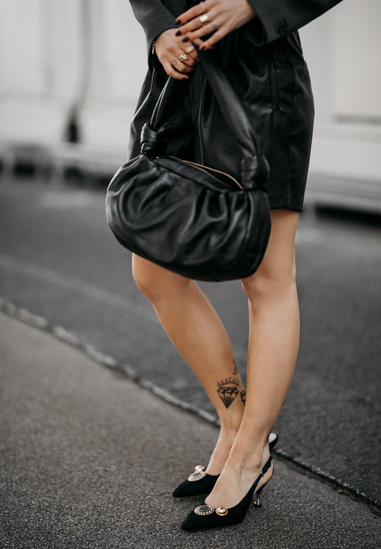 Summer streetstyle outfit by Masha Sedgwick wearing Blazer: MM6 Maison Margiela, black Leather shorts: SET, black slingback pumps & black Miu Miu puffed bag, grey basic logo shirt: Acne Studios | Minimalistic high end everyday outfit, effortless cool, summer outfit trends | Photo by Jeremy Moeller
