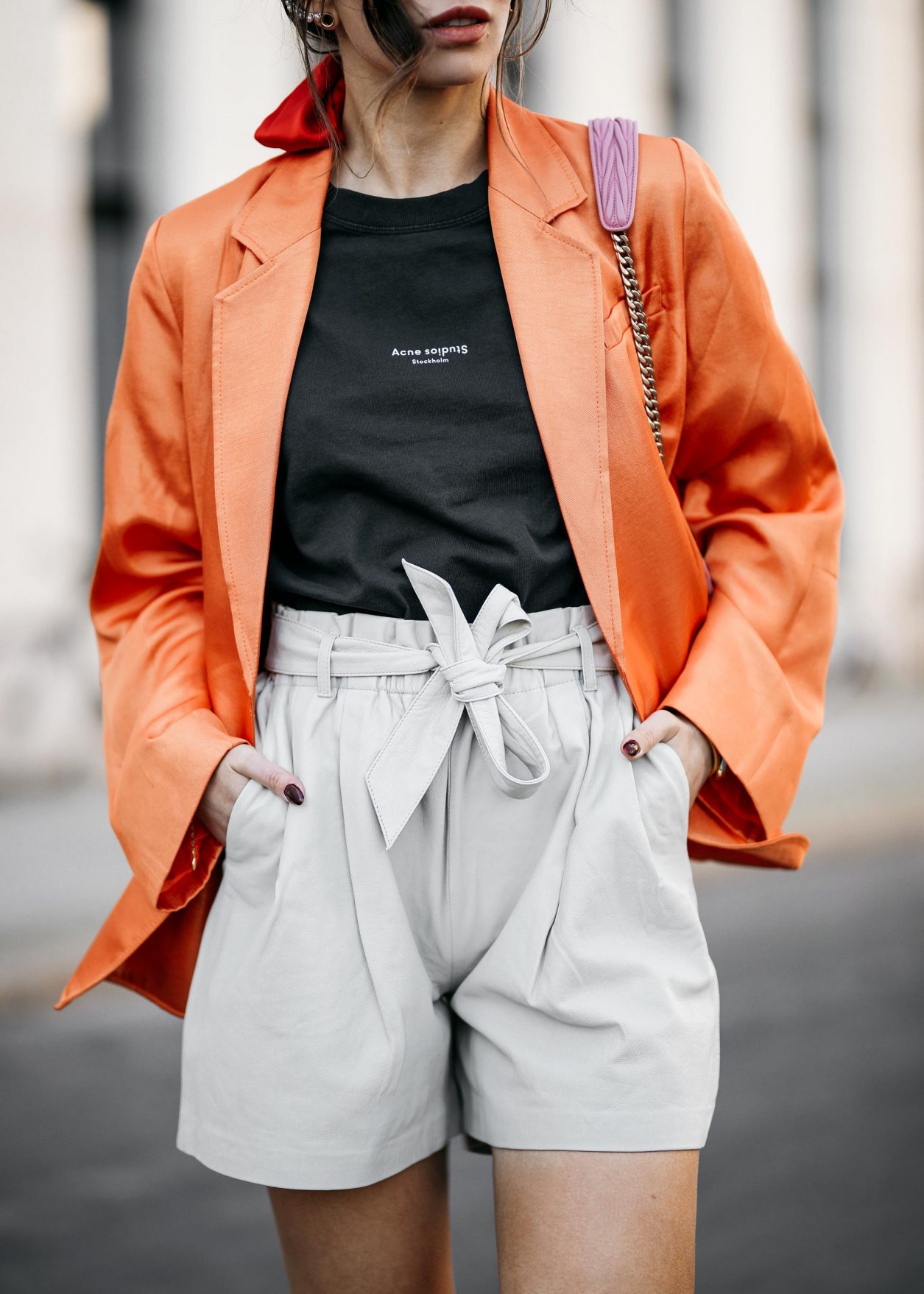 Summer Streetstyle Look by Masha Sedgwick | Photographer: Jeremy Moeller | Summer style trends & outfit inspiration, fashion blogger from Berlin, Germany | Wearing orange Baum Pferdgarten Blazer, graphic grey Acne Studios logo shirt, white leather Copenhagen Muse paperboy shorts, pink Miu Miu shoulder bag, red straps sandals by Charles & Keith | Hair style: messy ponytail