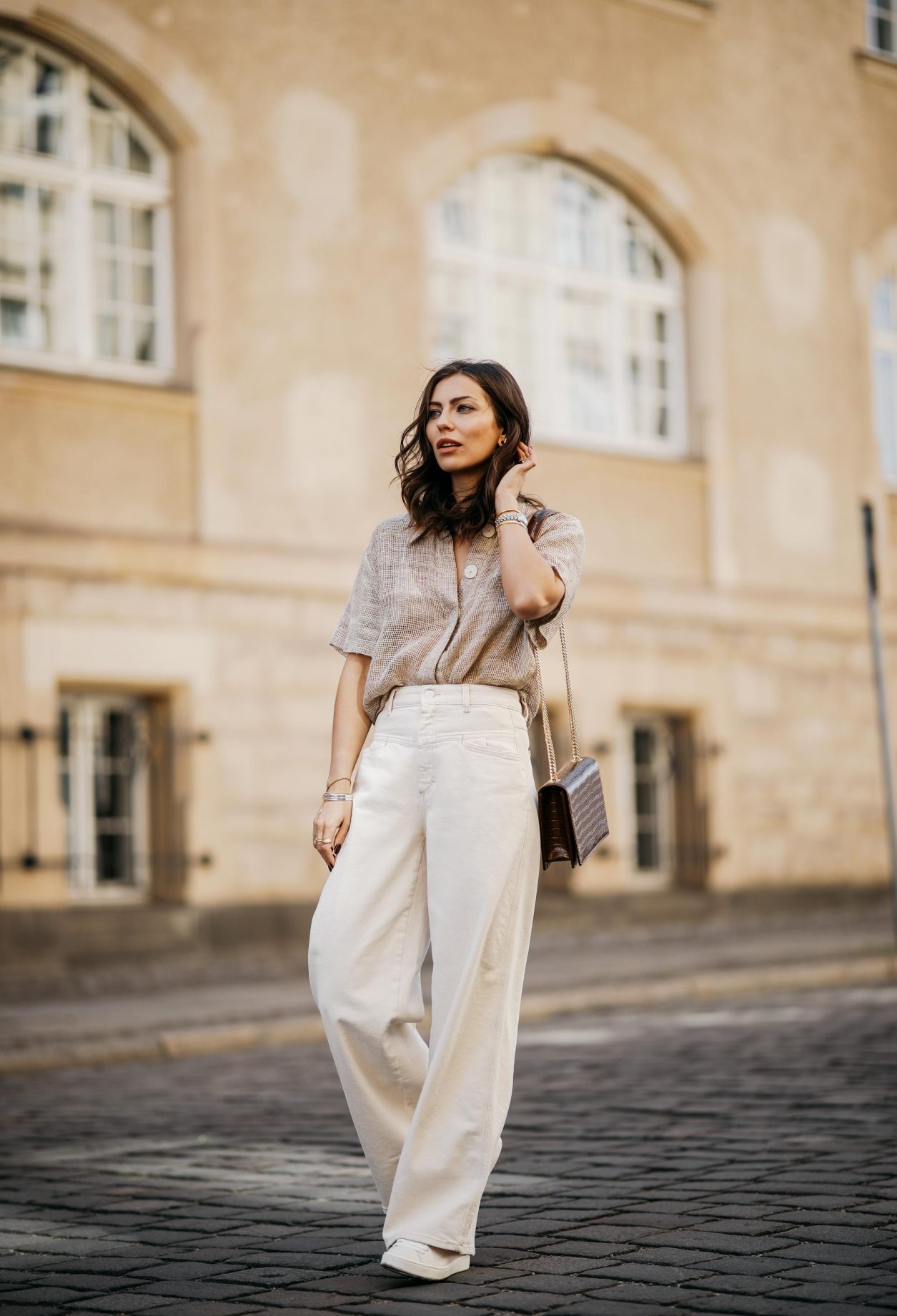 Streetstyle by Masha Sedgwick | Fashion and beauty blogger from Berlin, Germany | Everyday summer outfit inspiration, styling tips white sneakers, casual chic city look, white beige, effortless cool | Wearing wide white jeans, beige linen blouse shirt, cross body brown leather bag, white sneaker | Photographer Jeremy Moeller