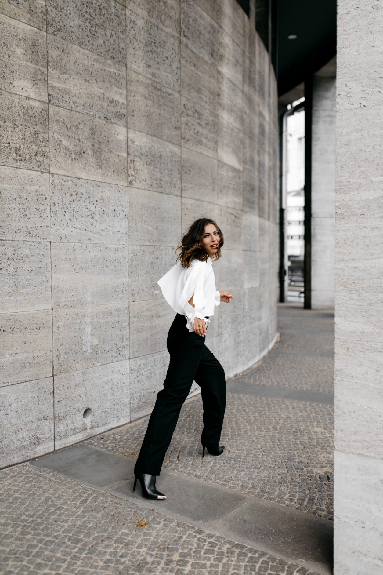 Anzeige | Streetstyle by Masha Sedgwick - fashion and beauty blogger from Berlin, Germany | Photographer Tonya Matyu | Minimalistic black and white outfit, business chic, high end, wearing black vintage Chanel wool pants, white cropped Nobi Talai blouse with puffed arms, dark day make-up, black leather high heels | Photo spot: Berlin Messe ICC 