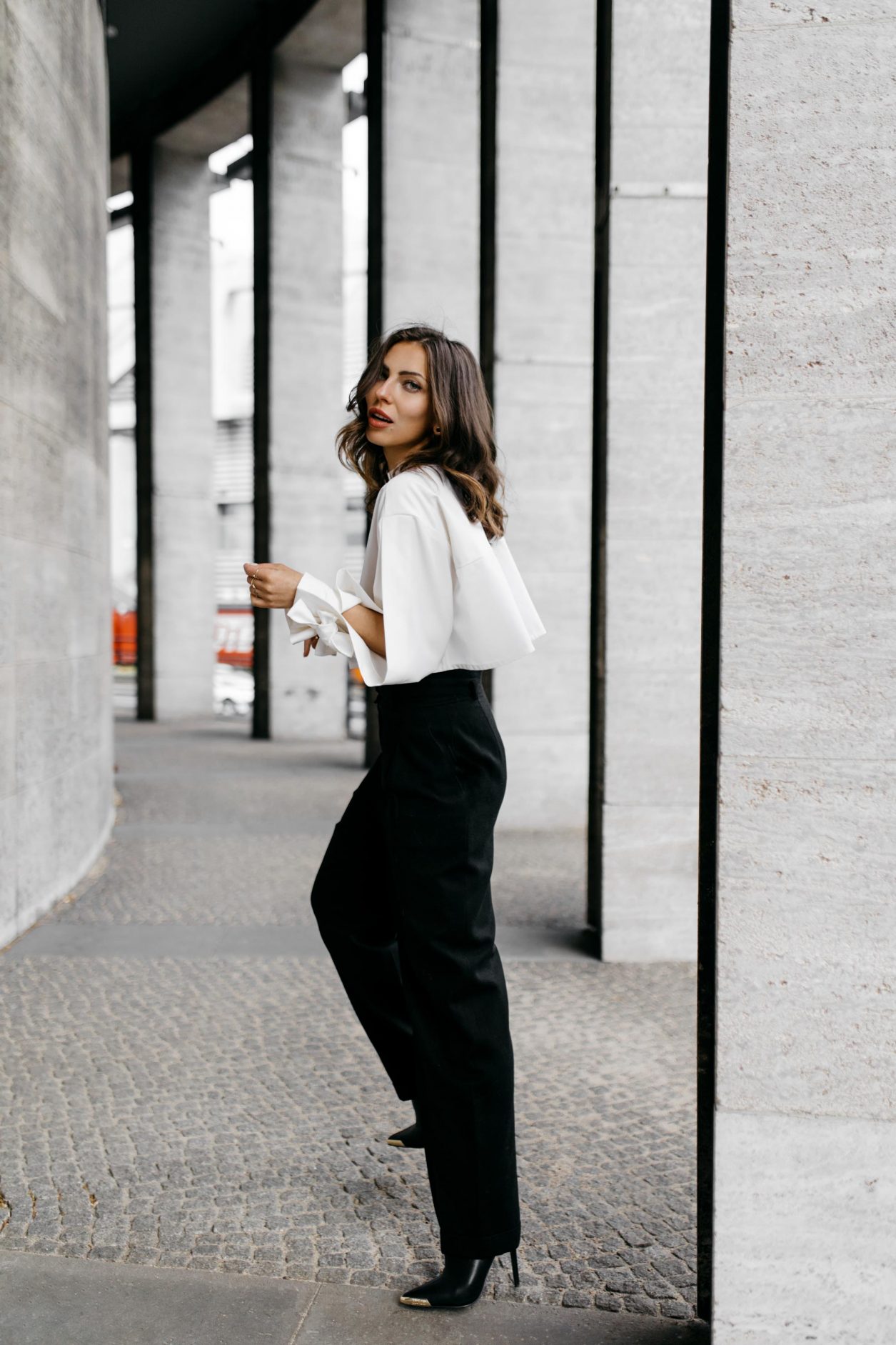 Anzeige | Streetstyle by Masha Sedgwick - fashion and beauty blogger from Berlin, Germany | Photographer Tonya Matyu | Minimalistic black and white outfit, business chic, high end, wearing black vintage Chanel wool pants, white cropped Nobi Talai blouse with puffed arms, dark day make-up, black leather high heels | Photo spot: Berlin Messe ICC 
