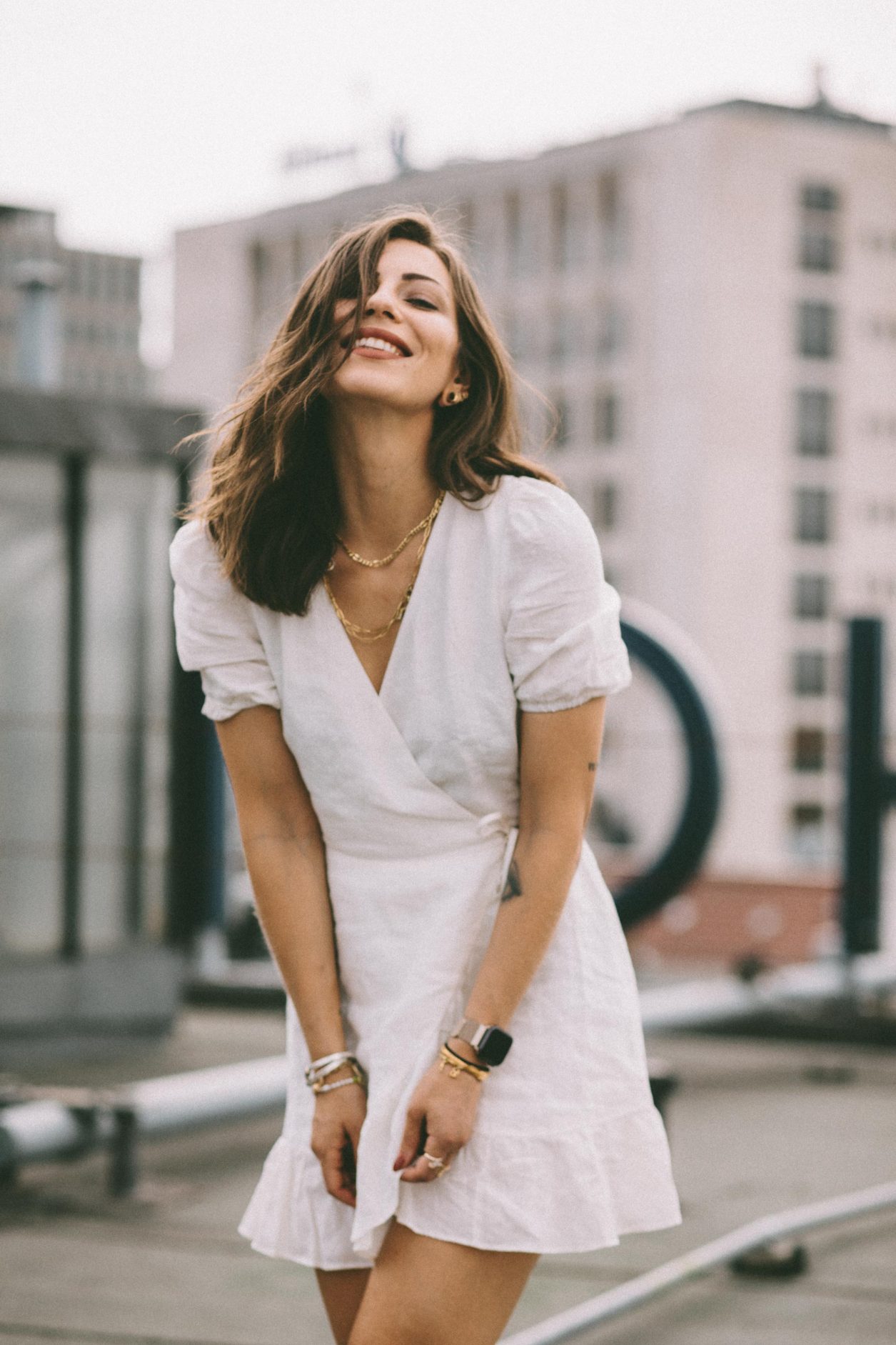 Anzeige | Fashion and beauty blogger from Berlin, Germany - Masha Sedgwick on the roof of Hotel Zoo, summer outfit inspiration: cute white linen wrapped mini dress, golden jewelry from Ariane Ernst, Thomas Sabo, Bulgari ring, white Coach sneaker | Inked fashion blogger, minimalistic, chic, effortless cool, streetstyle inspiration, ootd, photographer Tonya Matyu