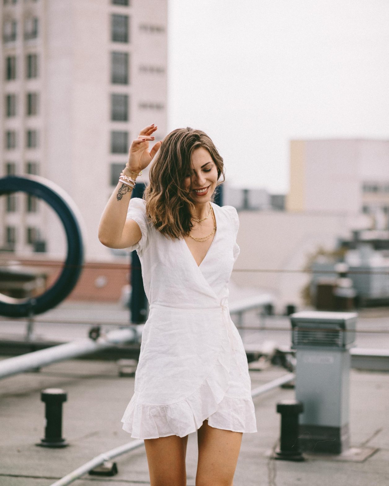 Anzeige | Fashion and beauty blogger from Berlin, Germany - Masha Sedgwick on the roof of Hotel Zoo, summer outfit inspiration: cute white linen wrapped mini dress, golden jewelry from Ariane Ernst, Thomas Sabo, Bulgari ring, white Coach sneaker | Inked fashion blogger, minimalistic, chic, effortless cool, streetstyle inspiration, ootd, photographer Tonya Matyu