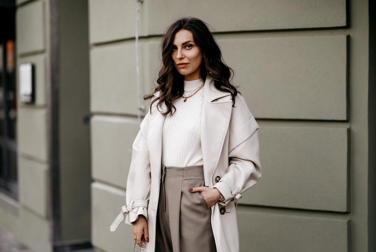 Spring Streetstyle outfit by Berlin fashion blogger Masha Sedgwick | Minimalistic, effortless cool, casual chic, wearing off white lack leather Apparis trench coat, off white Iris & Ink knit shirt, brown wide Frankie Shop pants with front pocket, lemon yellow WEAT crossbody mini bag, golden rings and necklaces, khaki green Charles & Keith pumps, hair style: black waves, photographer Jeremy Moeller 