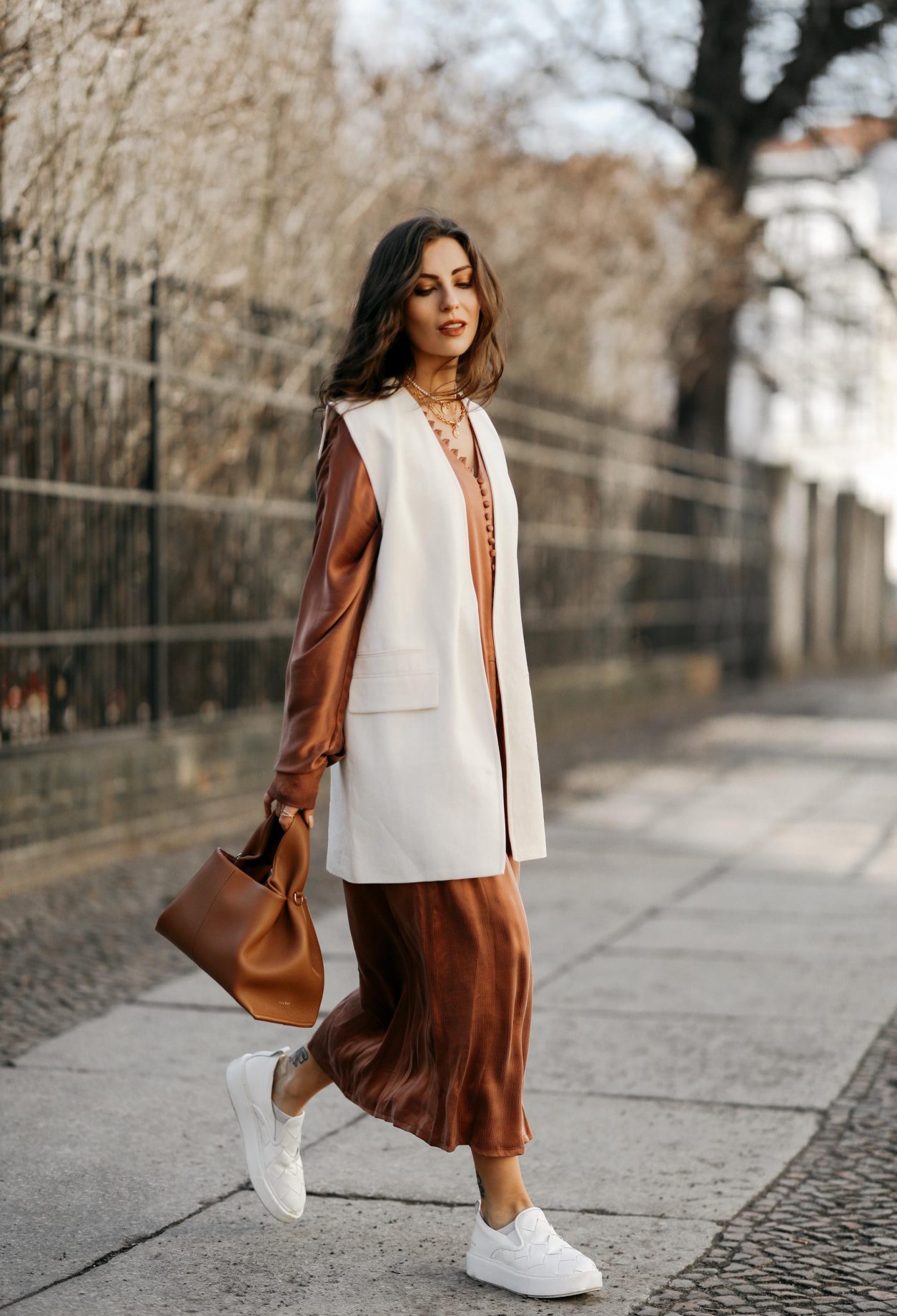 Streetstyle by Masha Sedgwick wearing bronze brown silk buttoned maxi dress by Envelope1976, white Zara blazer west, white slip-on Copenhagen studios sneaker, brown Polene Paris bag | Spring dress styling idea