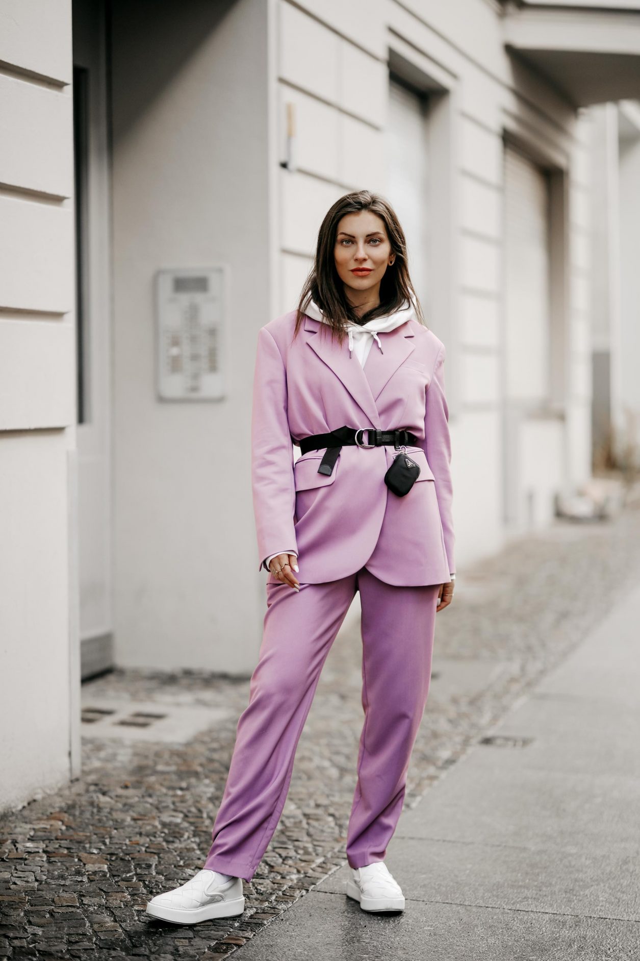 Streetstyle outfit by fashion blogger from Berlin, Germany | Minimalistic everyday outfit, business casual, spring suit ideas, spring colors, ss21 wardrobe must-haves, wearing lilac Market suit, Prada belt with belt-bag, white nail polish, white leather loafer, white hoodie 