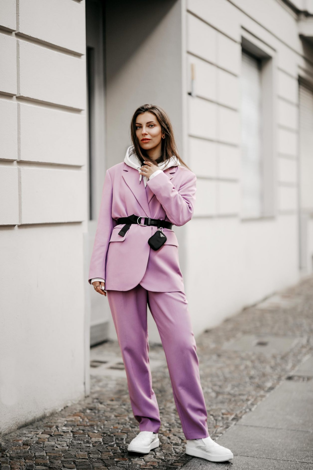 Streetstyle outfit by fashion blogger from Berlin, Germany | Minimalistic everyday outfit, business casual, spring suit ideas, spring colors, ss21 wardrobe must-haves, wearing lilac Market suit, Prada belt with belt-bag, white nail polish, white leather loafer, white hoodie 